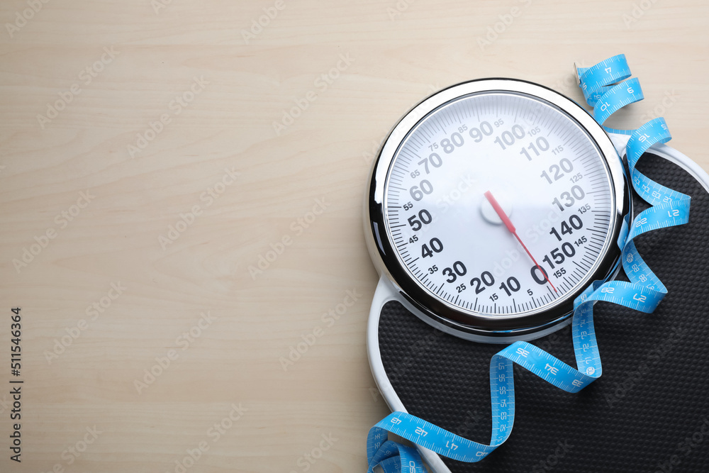 Sticker Bathroom scale, measuring tape and space for text on wooden floor, top view. Weight loss concept