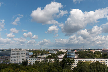 Fototapeta premium Bright beautiful white clouds against the midday blue sky over the city.