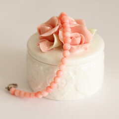 Pink coral bracelet and porcelain jewelry box isolated on white background, on table.	