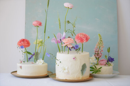 Close-up of different sized beautiful decorated with flowers cakes on a blue background