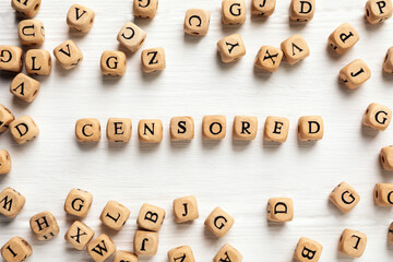 Wooden cubes with word Censored on white table, flat lay
