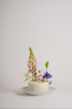White cake for one person decorated with flowers with lupine