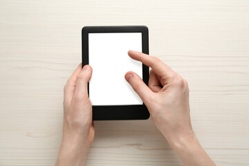 Woman using e-book reader at white wooden table, top view