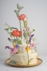 Multilevel large white cake on a light background decorated with fresh flowers