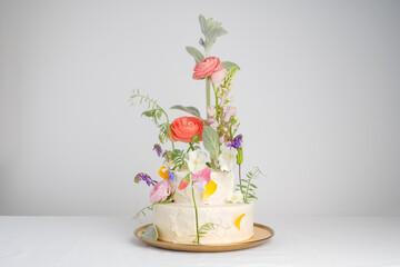 Elite wedding cake with a mix of fresh flowers, many levels, on a light background with space for...