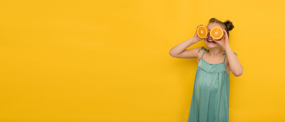 a happy girl in summer clothes holds orange pops in front of her eyes on a yellow background, a smiling girl made binoculars from oranges