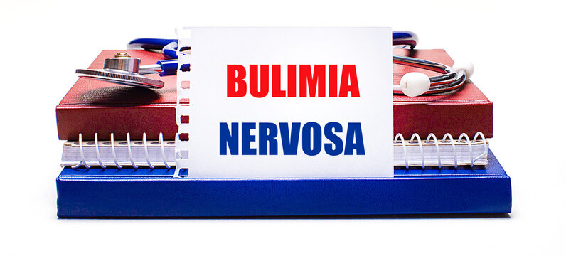On a light background notepad, a stethoscope and a white card with the text BULIMIA NERVOSA. Medical concept