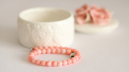 Pink coral bracelet and porcelain jewelry box isolated on white background, on table.	