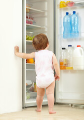 Fototapeta na wymiar Snack time. Shot of a toddler eating food from the fridge.