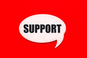 On a bright red background, a light wooden curly card with the text SUPPORT