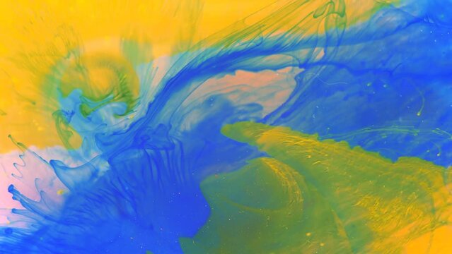 Moving background consisting of blue, yellow and green particles of the current paint on a white background. Fluid art.
