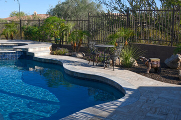 A desert landscaped yard in Arizona featuring a travertine tile pool deck.