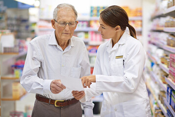 Keeping her customers informed. Shot of a young pharmacist helping an elderly customer with his...