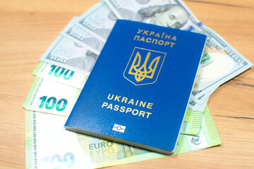 Ukrainian biometric passport id to travel the Europe with dollars and euros money on the table. Inscription in Ukrainian "Ukraine Passport". Travel or migrants concept.