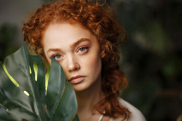 Close-up face of a beautiful young woman with red hair and freckles.