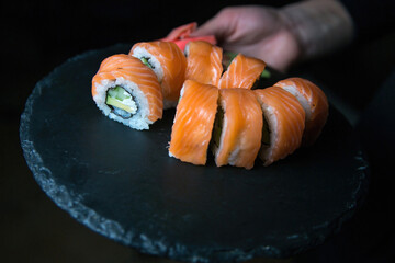 Philadelphia sushi roll with salmon, cucumber, avocado, cream cheese. Sushi menu. Japanese food. On a plate. On dark background.