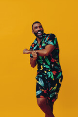 handsome bearded mid adult african american man smiling and dancing wearing Hawaiian shorts and...