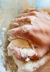 Woman hand kneading dough in bowl sprinkled with flour