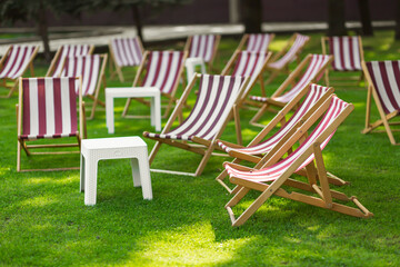 Striped sun loungers and a table in the park on the grass.