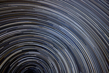 Star Trails night sky background, sweeping curves of concentric white and blue against a dark background.