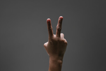 One hand pointing two finger symbolic peace with spotlight effect and isolated dark grey background