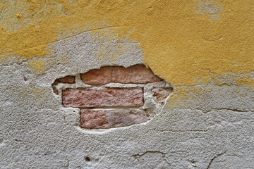 Mur jaune ancien avec enduit manquant et briques apparentes. - obrazy, fototapety, plakaty