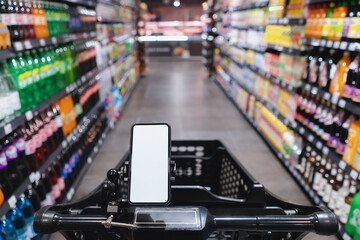 Closeup on a mobile phone clipped on the shopping cart with blurred supermarket aisle view.