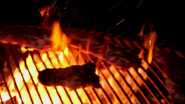 Fried juicy meat steak with spices and herbs in burning coals on a barbecue grill. Rotary grill, slow motion. Culinary concept. Very satisfying protein delicious steak on an open fire