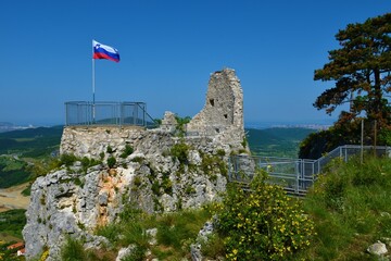 View of the ruins of Crni Kal fortress at Karst Edge in Primorska, Slovenia with yellow flowering...