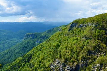 Fototapeta na wymiar View of forest covere mountain slopes above Kolpa valley in Slovenia and Risnjak mountains in Croatia behind
