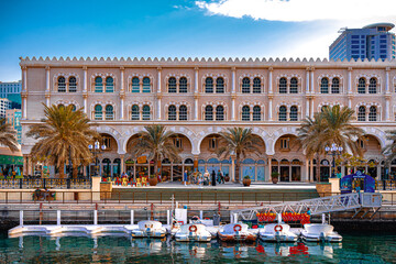 10 Jan 2022 - Sharjah, UAE: Al-Qasba shopping center and boats for rent in Al-Qasba waterway canal. - obrazy, fototapety, plakaty