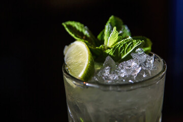 Mojito, cocktail close-up on a black background. Lime slice, mint and ice