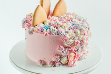 gingerbread cookies on the top of pink birthday cake decorated with cream cheese flowers. Colorful cake for a little girl on the white background