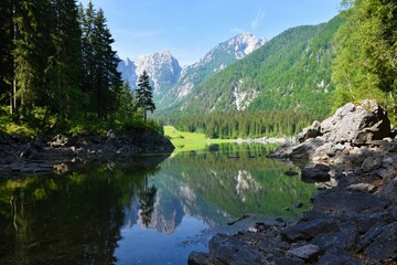 View of a bay at Laghi di Fusine Superiore in Comune di Tarvisio in Italy and forest covered mountains