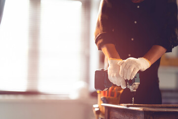 Male mechanic using a cordless screwdriver drill with wood screws in the workshop.