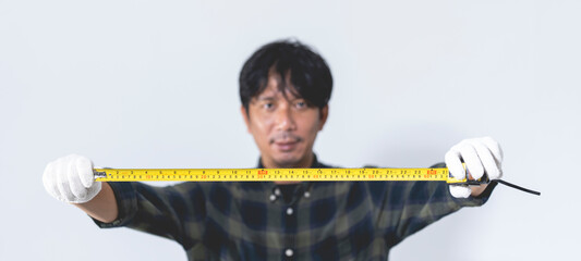 Male mechanic holding a tape measure against a white background. Isolated image.