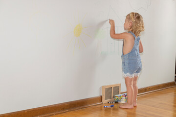 Naughty child coloring on the walls inside her home and not doing what she is suppose to do