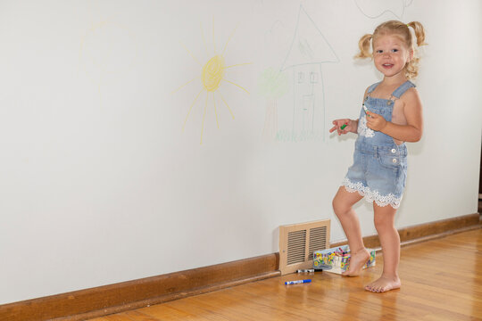 Naughty child coloring on the walls inside her home and not doing what she is suppose to do