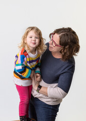 Mother and daughter laughing and being silly during a photo session in studio on a white background
