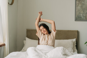 Portrait of a brunette woman arms high up in the air waking up in the morning