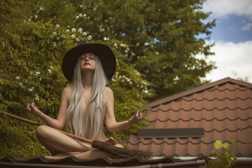 Obraz premium Young beautiful and mysterious Witch woman Flying on the Broom. Levitation, a witch in a hat flies on a broom, free space. Halloween holiday, magic