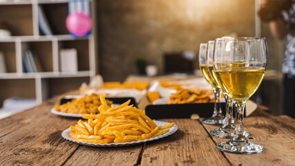 Desk of pizza party, crispy, french fry and white wine glasses wear on old weathered wooden desk in business office.