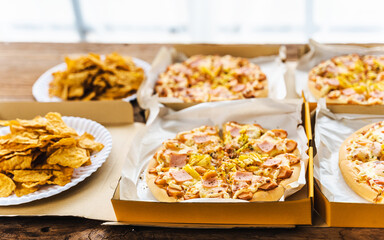 Desk of pizza party, crispy, french fry and white wine glasses wear on old weathered wooden desk in business office.
