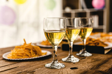 Desk of pizza party, crispy, french fry and white wine glasses wear on old weathered wooden desk in business office.