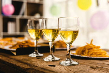 Desk of pizza party, crispy, french fry and white wine glasses wear on old weathered wooden desk in business office.