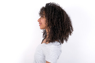 Profile portrait of nice Young beautiful girl with afro hairstyle wearing grey t-shirt over white wall look empty space toothy smile