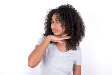 Young beautiful girl with afro hairstyle wearing gray t-shirt over white background cutting throat...