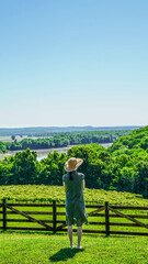 Woman in sunhat standing in a vineyard overlooking a valley