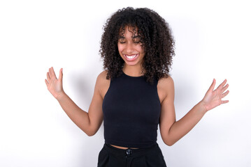 Emotive Young beautiful girl with afro hairstyle wearing black tank top over white background...