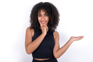 Funny Young beautiful girl with afro hairstyle wearing black tank top over white background hold...